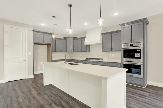 a view of an empty room with kitchen and window
