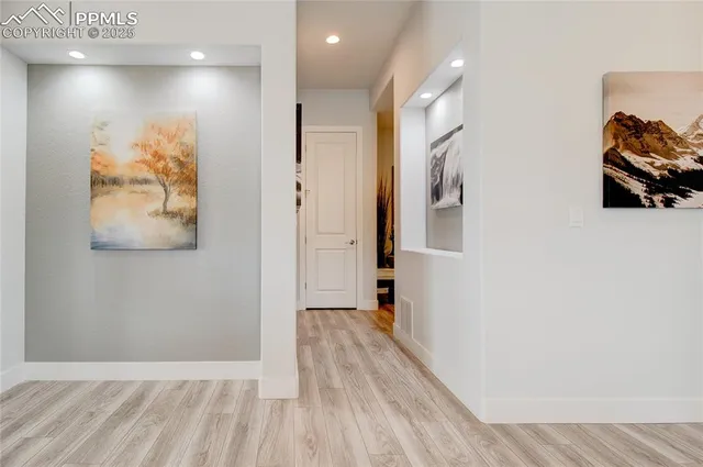 a view of a hallway with wooden floor and a bathroom