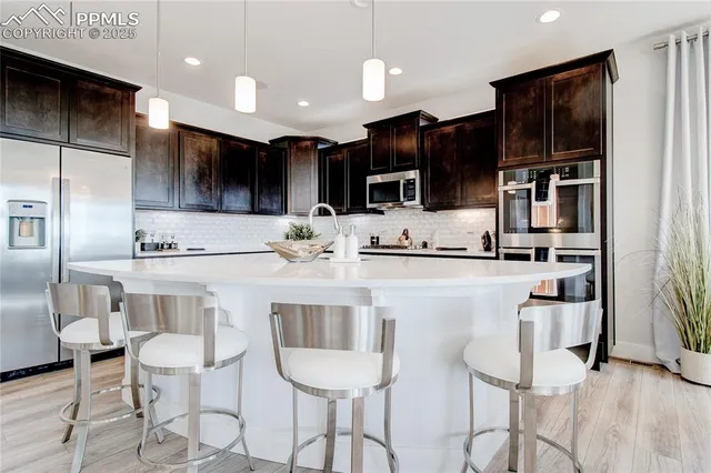 a kitchen with stainless steel appliances kitchen island granite countertop a dining table chairs refrigerator and sink