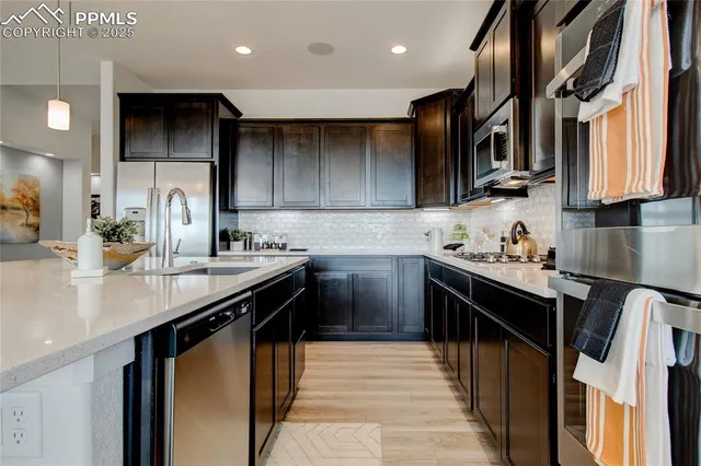 a kitchen with stainless steel appliances granite countertop a sink a stove and a refrigerator
