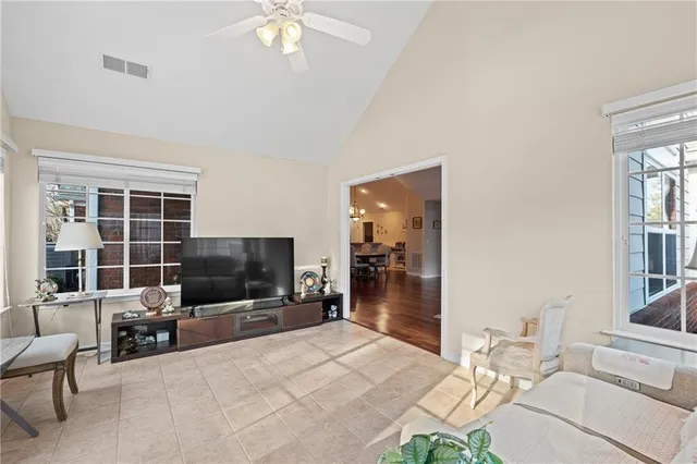 a living room with furniture a flat screen tv and floor to ceiling window