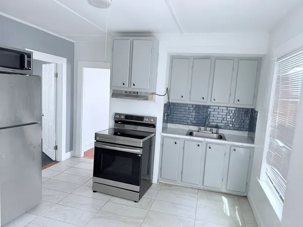 a kitchen with granite countertop a stove top oven and cabinets