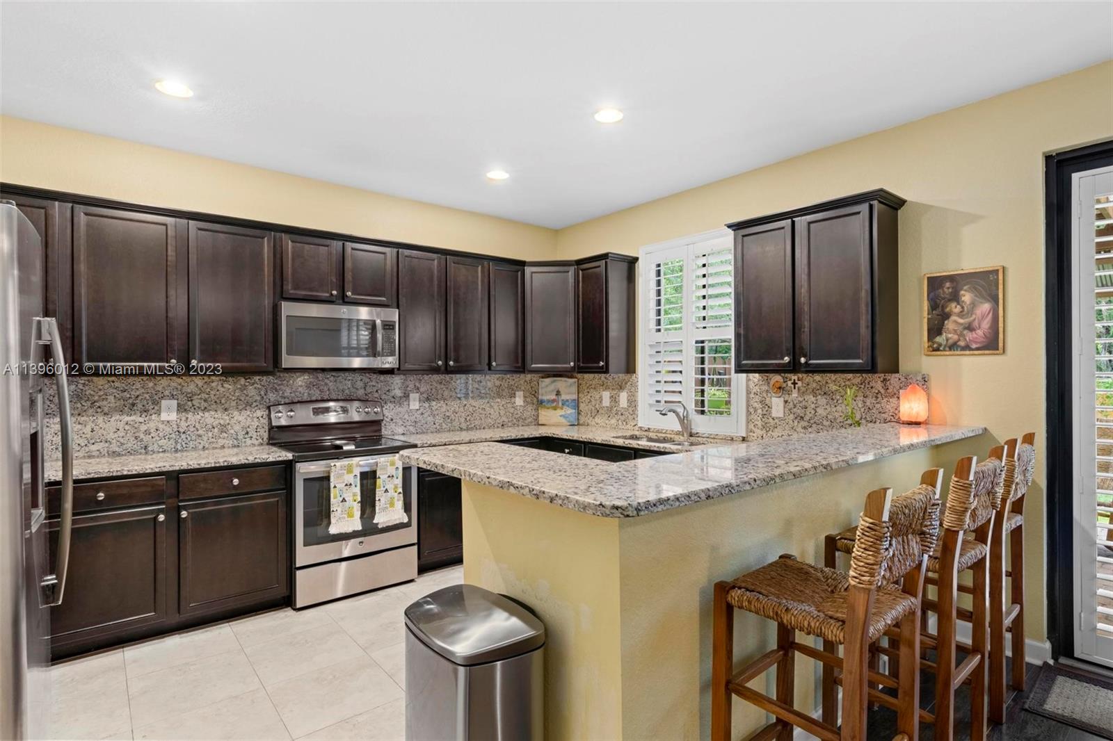 12120 Village Place Davie, FL 33325 - Photo 22 of 35 a kitchen with stainless steel appliances granite countertop a stove a sink a microwave a refrigerator and cabinets