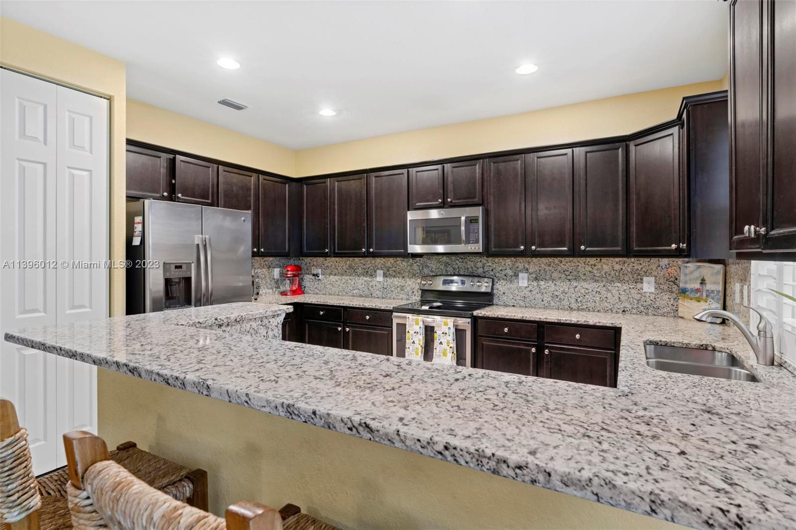 12120 Village Place Davie, FL 33325 - Photo 23 of 35 a kitchen with granite countertop wooden cabinets a refrigerator and a sink
