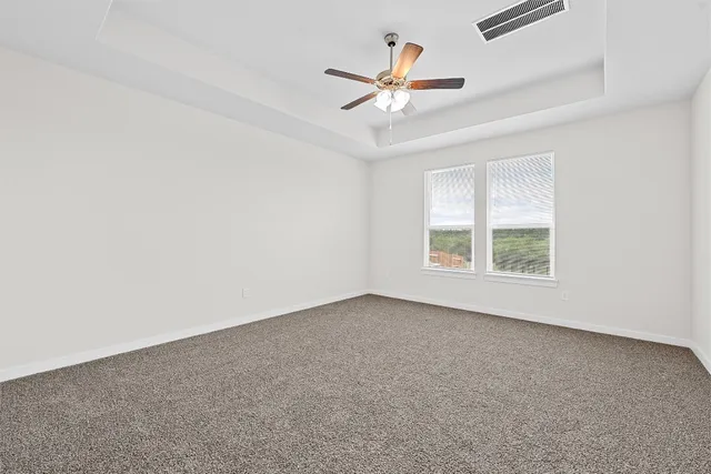 an empty room with windows and fan