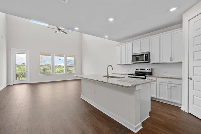 a kitchen with stainless steel appliances granite countertop a stove top oven a sink dishwasher and a refrigerator with wooden floor