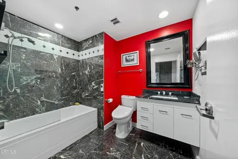 a bathroom with a granite countertop sink mirror vanity and toilet