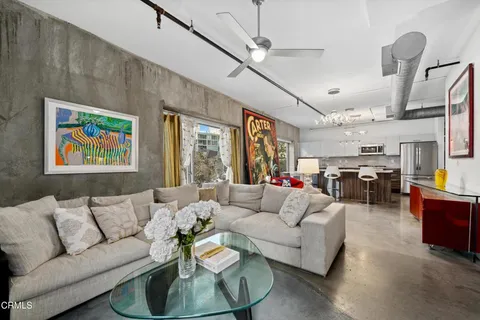 a living room with furniture kitchen view and a chandelier