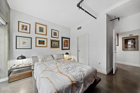 a bedroom with a bed and a lamp on the dresser