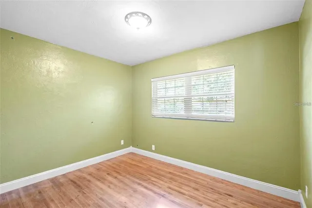 an empty room with wooden floor and fan