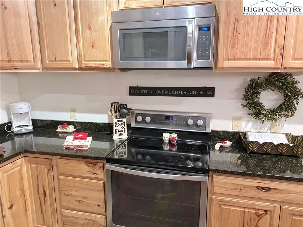 702 Pine Ridge Road Beech Mountain, NC 28604 - Photo 9 of 24 a kitchen with granite countertop white cabinets and black appliances