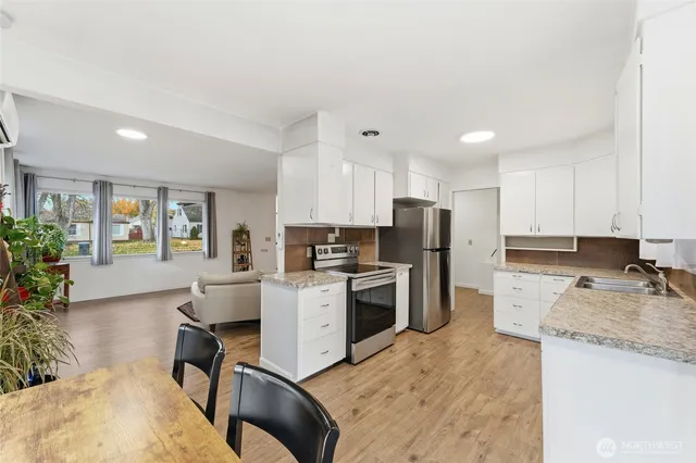 a kitchen with a sink a stove a refrigerator cabinets and a dining table
