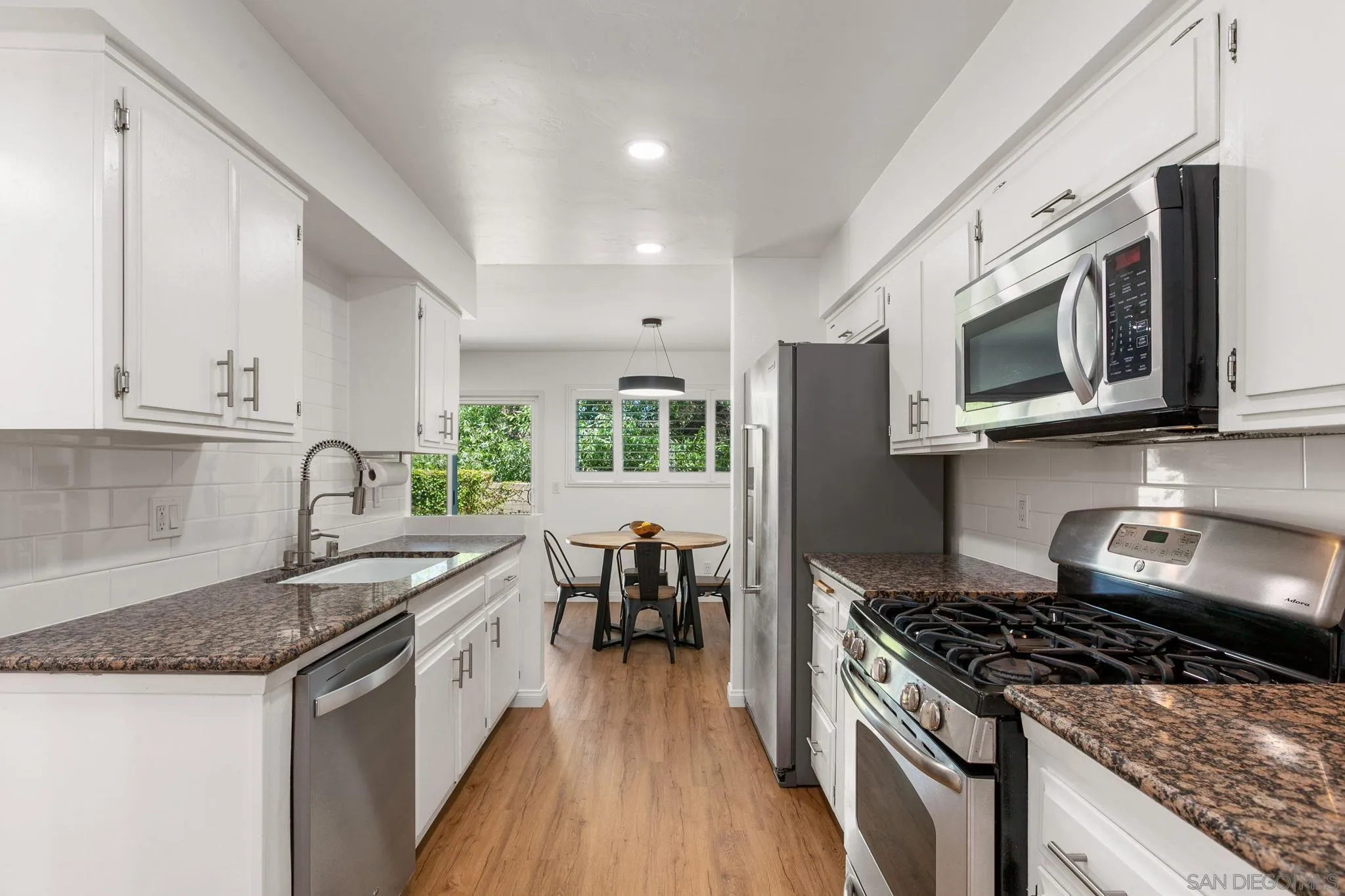 a kitchen with stainless steel appliances granite countertop a stove a sink and a microwave