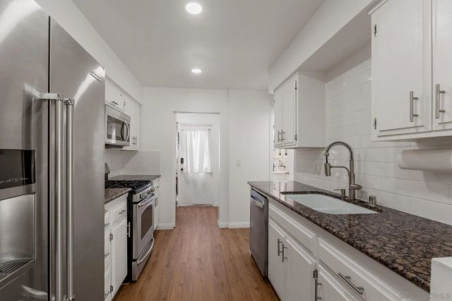 a kitchen with stainless steel appliances granite countertop a refrigerator a stove and a sink