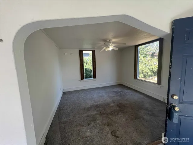 an empty room with windows and chandelier fan