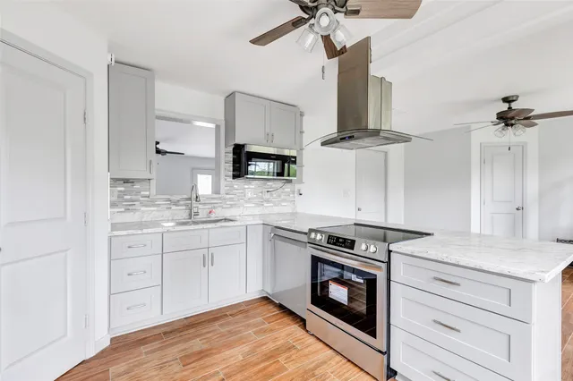 a kitchen with stainless steel appliances a stove and white cabinets
