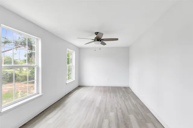 a view of empty room with wooden floor and fan