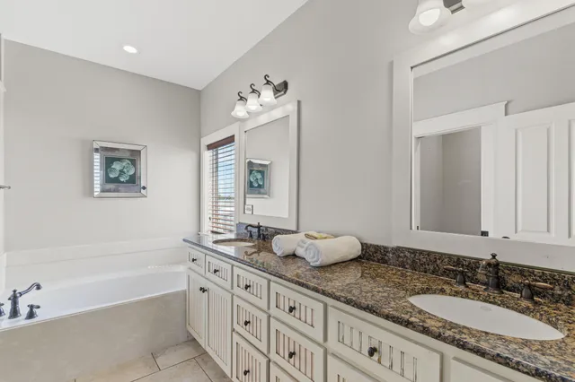 a bathroom with a granite countertop double vanity sink and a bathtub