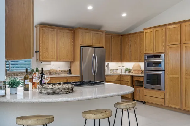 a kitchen with kitchen island granite countertop wooden cabinets and stainless steel appliances