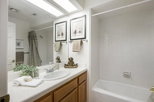 a bathroom with a granite countertop sink mirror and a bath tub