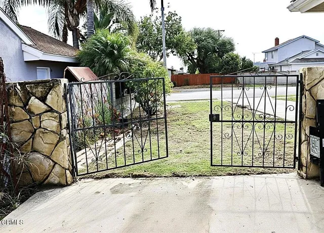 a view of a brick house with a large window and wooden fence
