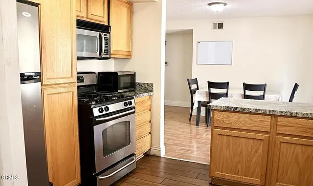 a kitchen with stainless steel appliances kitchen island granite countertop a stove and a refrigerator