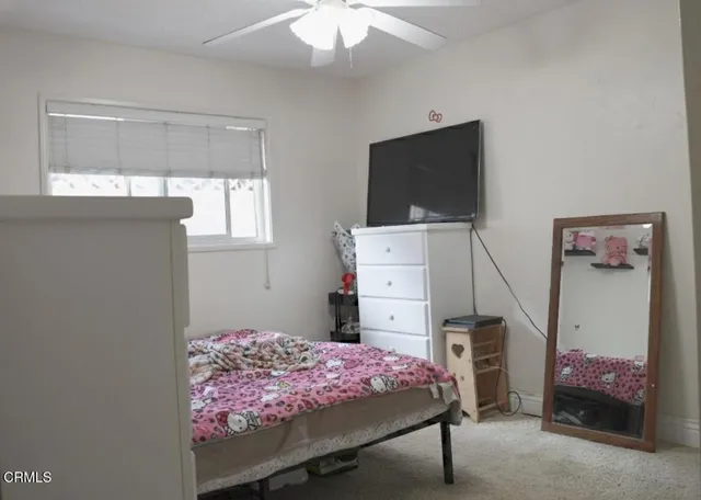 a bedroom with a bed and a flat tv screen on dresser