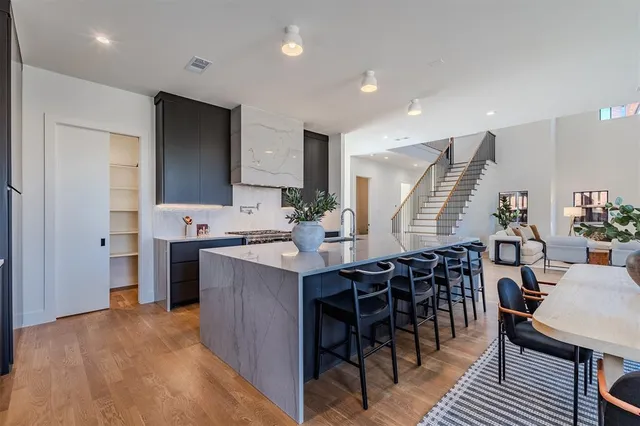 a kitchen with stainless steel appliances kitchen island granite countertop a table chairs and a refrigerator