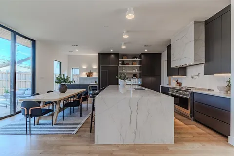 a large kitchen with kitchen island a stove a sink a table and chairs in it