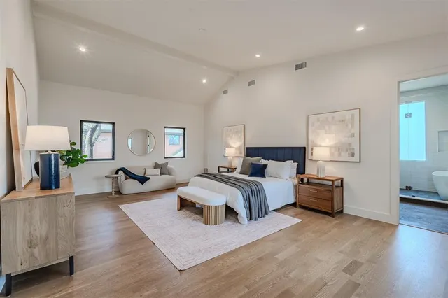 a spacious bedroom with a bed and wooden floor