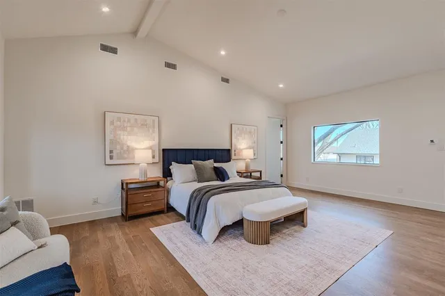 a spacious bedroom with a bed and wooden floor