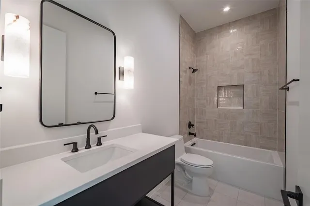 a bathroom with a bathtub shower sink vanity mirror and toilet