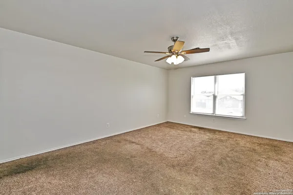 an empty room with windows and chandelier fan