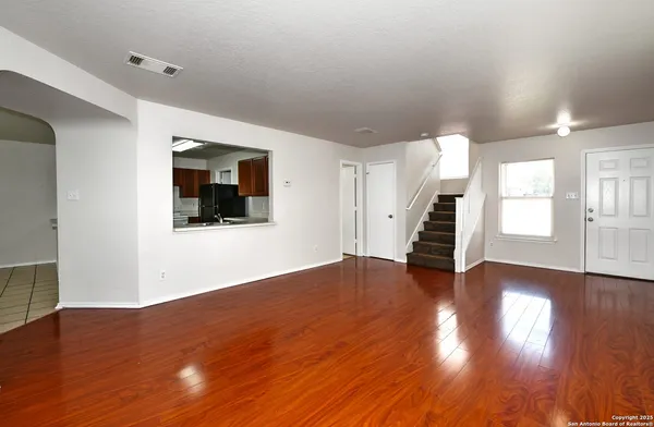 a view of an empty room with wooden floor and stairs