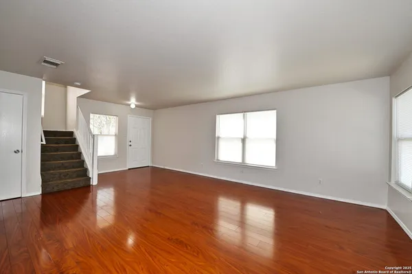 a view of an empty room with wooden floor and a window