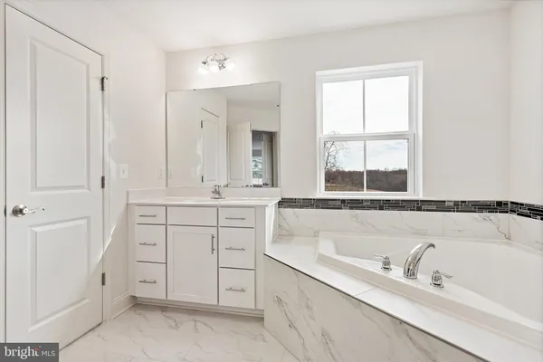 a bathroom with a tub sink and mirror