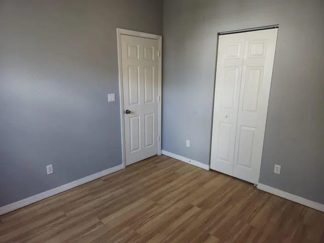 an empty room with wooden floor windows and fan