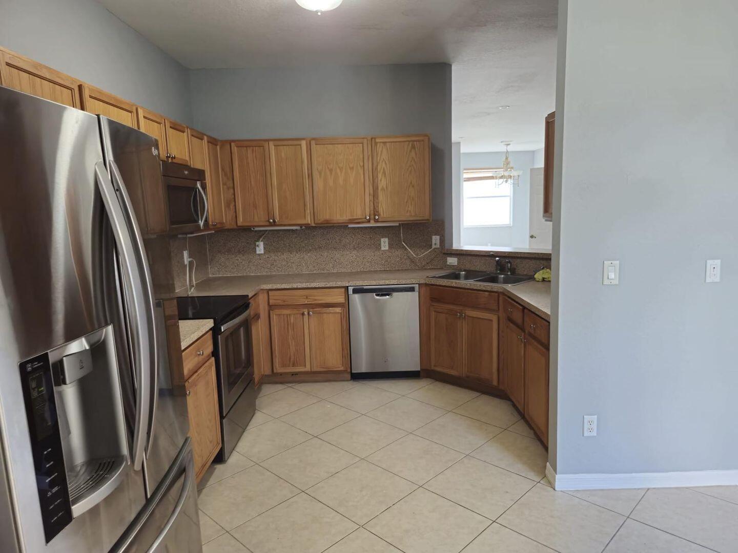 3123 Grandiflora Drive Greenacres, FL 33467 - Photo 9 of 49 a kitchen with stainless steel appliances a sink stove and refrigerator