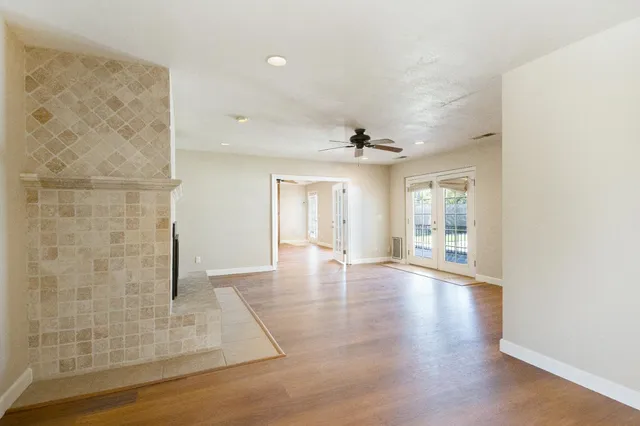 an empty room with wooden floor fan and windows