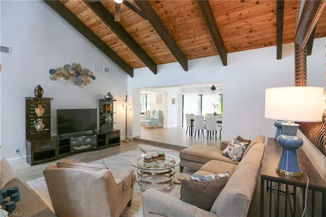 a living room with furniture a flat screen tv and a floor to ceiling window