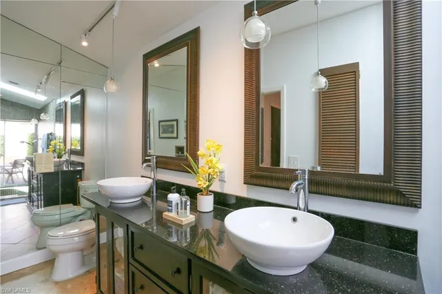 a bathroom with a granite countertop sink mirror vanity and toilet