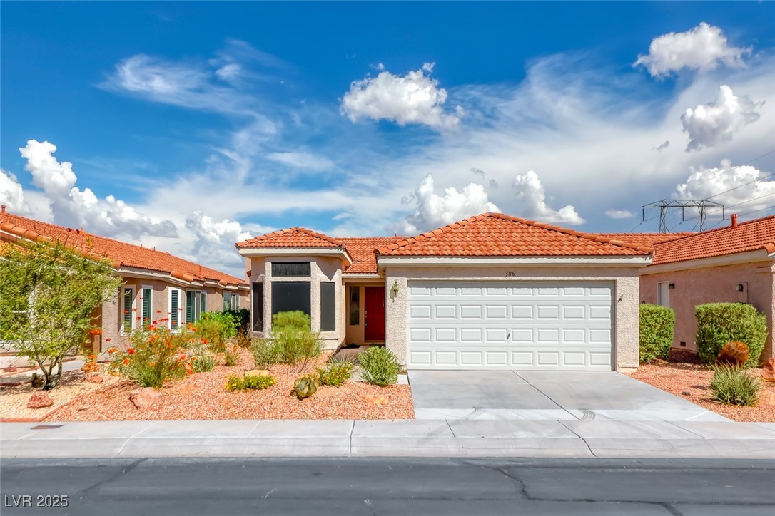 Mediterranean / spanish house featuring a tile roof, stucco siding, a garage, and concrete driveway
