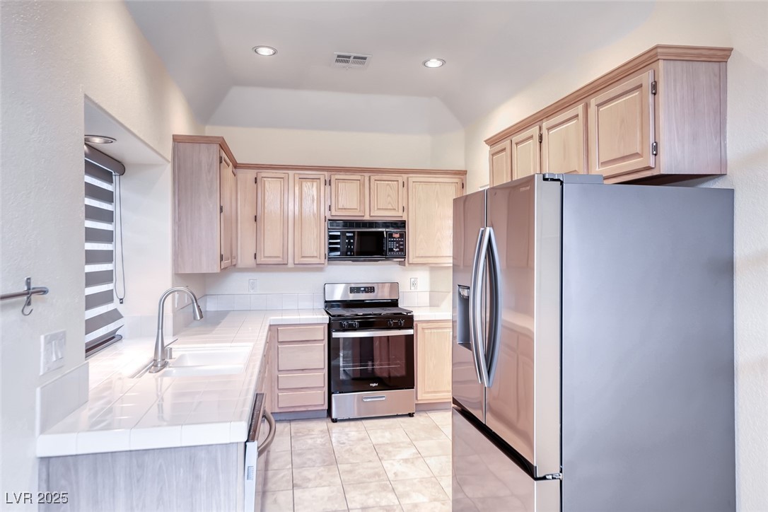 386 Nassau Way Boulder City, NV 89005 - Photo 15 of 44 Kitchen featuring light brown cabinets, stainless steel appliances, tile countertops, light tile patterned floors, and recessed lighting