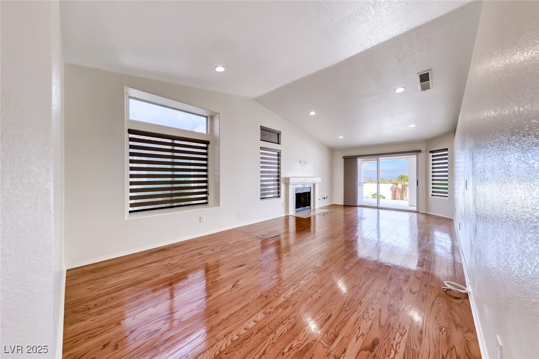 386 Nassau Way Boulder City, NV 89005 - Photo 32 of 44 Unfurnished living room featuring a fireplace with flush hearth, light wood-style flooring, and lofted ceiling