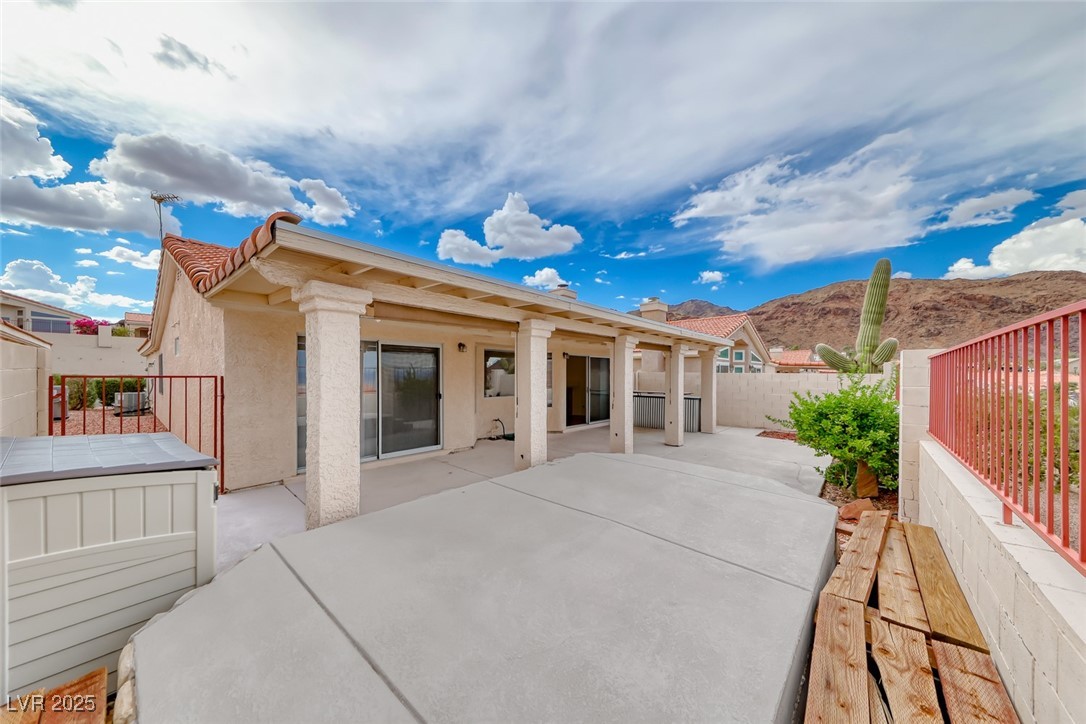 386 Nassau Way Boulder City, NV 89005 - Photo 6 of 44 Rear view of property with stucco siding, a fenced backyard, a patio, a mountain view, and a hot tub