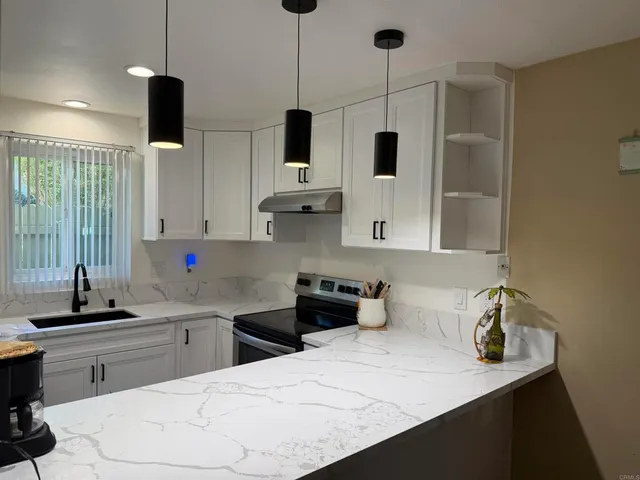 a kitchen with stainless steel appliances kitchen island granite countertop a sink a stove and a refrigerator