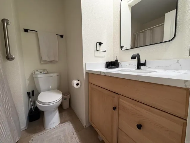 a bathroom with a granite countertop toilet sink and mirror