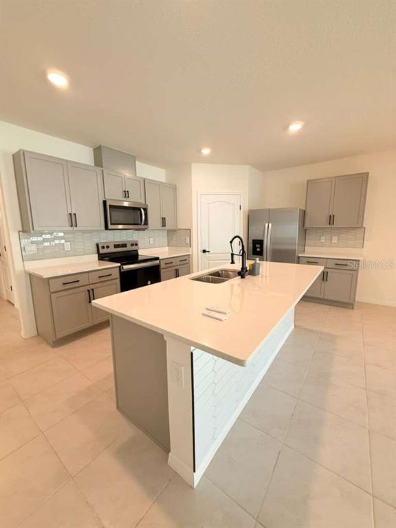 2518 Trinidad Road Haines City, FL 33844 - Photo 5 of 17 a kitchen with stainless steel appliances a sink a stove a microwave a center island and cabinets
