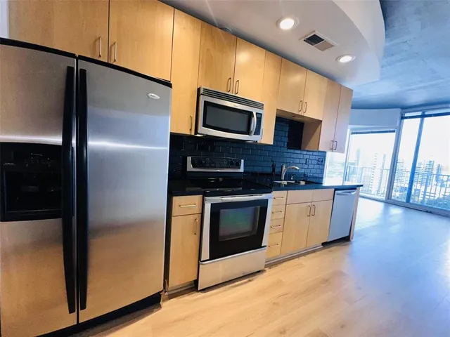 a kitchen with stainless steel appliances kitchen island wooden floors and white counter top