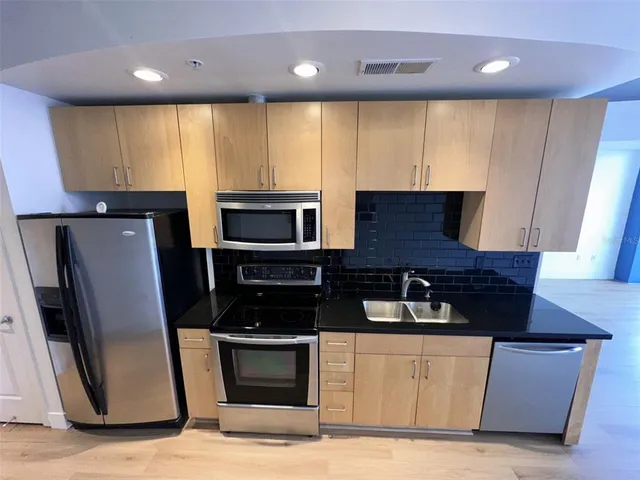 a kitchen with stainless steel appliances a refrigerator sink and microwave